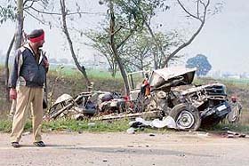 A policeman looks at the mangled remains of a tempo that was hit by a bus, killing all six occupants and the driver, at Tangra village, 35 km from Amritsar