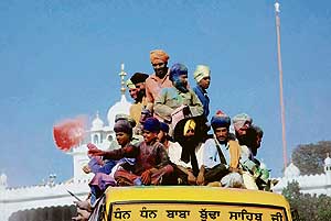 A Nihang Singh throws colour on devotees during a procession at Anandpur Sahib on the concluding day of Hola Mohalla on Sunday.