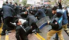 Police officers beat lawyers with batons during an anti-government rally in Lahore on Monday