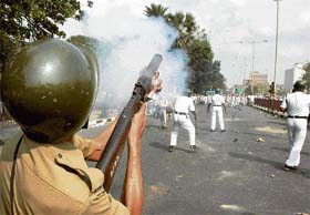 A policeman fires teargas shells to control a mob led by Jamait-e-Ulema-Hind members during their protest against Nandigram violence in Kolkata