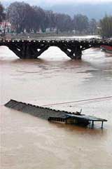 Only the roof of a partially sunk houseboat is visible on the Jhelum during heavy rainfall on Tuesday