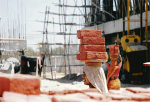 A woman carries bricks over her head at a construction site near Chandigarh.