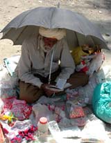 An old man reciting Japuji Sahib under an umbrella near a road outside a private school in Amritsar on Tuesday.