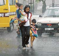 A woman and children run for shelter from rain in Patiala on Friday.