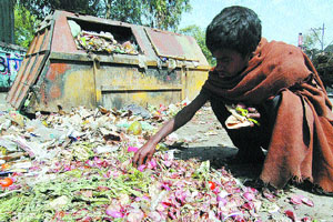 A begger looks for eatables in a garbage dump.