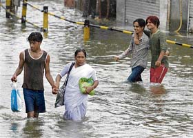 People walk through a waterlogged street in Mumbai