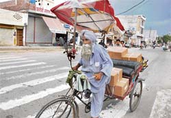 Necessity is the mother of invention: An aged rickshaw-puller protects himself from the scorching heat by “inventing” a colourful umbrella for himself in Bathinda on Friday.