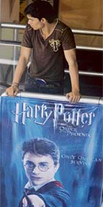 A cinema employee stands beside a poster advertising the latest film featuring the character Harry Potter at a cinema in Mumbai