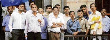 People watch a large screen displaying the stock index at the Bombay Stock Exchange building in Mumbai