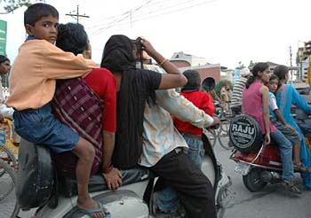 A family mounted on a scooter waits for the traffic light to turn green in Amritsar on Friday.