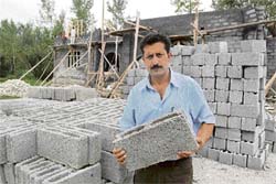 A.R. Rafiqi shows grey blocks he makes from concrete cement aggregate