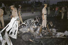 Security forces jawans inspect the damaged car which was blasted by militants in Srinagar