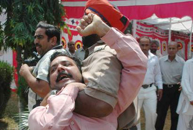 A policeman has a teacher firmly in his grip during a protest in Kapurthala on Wednesday.
