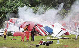 Rescue workers stand next to the wreckage of Thai budget carrier One-To-Go MD-82 plane after it crashed at Phuket airport in Phuket island on Sunday.