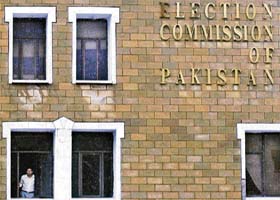 A staff member of the Pakistan EC stands at a widow of his office in Islamabad