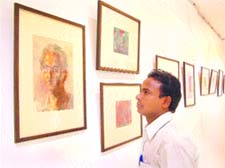 A visitor takes a close look at the paintings by late C.L. Sharma at Dr Satya Paul Art Gallery in Jalandhar on Thursday