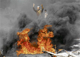 A supporter of Benazir Bhutto gestures next to a bonfire during a protest against Fridays bombing incident in Karachi on Saturday.