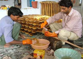Employees of a sports goods manufacturing unit in Jalandhar using a condom to make the hook of a hockey stick more durable