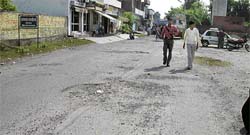 A view of a potholed road dividing Geeta Colony and HUDA Sector 17 at Kurukshetra.
