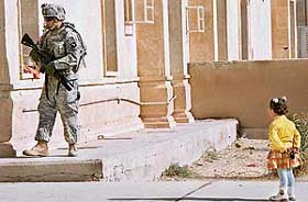A student stands at ease as a US soldier with Alpha Companys First Special Troops Battalion, 101st Airborne, visits a school during a patrol in south Tikrit