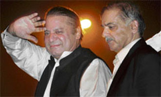 Former Pakistan Prime Minister Nawaz Sharif is watched by his brother Shahbaz Sharif (right) as he salutes his supporters outside the Allama Iqbal International Airport in Lahore on Sunday after their arrival from Saudi Arabia.