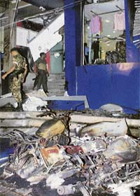 Security personnel walk amongst burnt out vehicles outside a shattered store front in Colombo on Wednesday after an explosion on the outskirts of the Sri Lankan capital