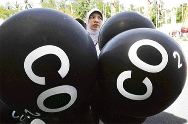 An activist carrying black balloons, representing CO2 emission, demonstrates outside the venue of the climate change conference in Nusa Dua, Bali island, on Saturday.