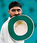 Has he bitten too much? Harbhajan Singh walks with his hat in his mouth after finishing an over at the SCG on Saturday.