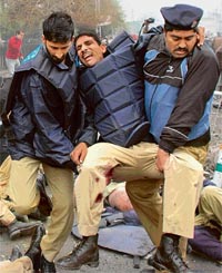 Policemen carry away an injured colleague from the scene where a powerful bomb exploded near the High Court in Lahore on Thursday.