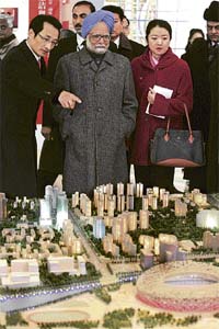 Prime Minister Manmohan Singh looks at a replica of the National Olympic Stadium, also known as "Bird's Nest", as Beijing Vice-Mayor Chen Gang (left) explains it in Beijing