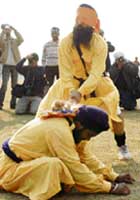 A Nihang Sikh cuts an apple placed on the back of other