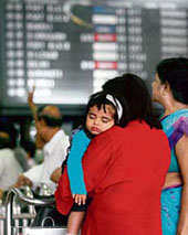 Passengers watch the flight schedule following a nationwide call to cease work by workers at the ticket counter of Netaji Subhas Chandra Bose Airport in Kolkata on Wednesday.