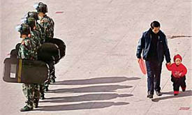 A Chinese man and a young girl walk behind riot policemen standing guard in Kangding county, the capital of Ganzi Tibetan Autonomous Prefecture, in Chinas south-western Sichuan province on Thursday.