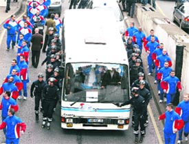 Police security personnel run beside the bus on which the torch was placed after it set off from the Eiffel Tower.