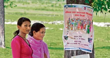 Nepalese women stand near an election poster at Jhiljhiley village in Eastern Nepal