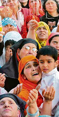 Kashmiri Muslim women reach towards an unseen priest as he displays a relic at the shrine of Sheikh Abdul Qadir Geelani in Srinagar on Friday.