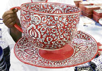 A craftsman displays a giant cup and a saucer at a handicraft fair in Chandigarh