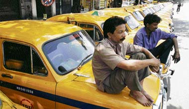 Taxi drivers rest on their vehicles during a strike in Kokata