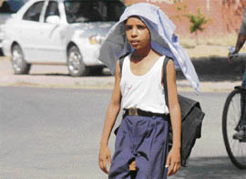 With the mercury crossing 40° C, a school student covers head with his shirt to save himself from the scorching heat in Chandigarh.