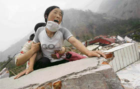 A woman cries as she cannot find her four-year-old daughter and husband on the top of the ruins of a damaged school in earthquake-hit Beichuan county, Sichuan province, on Saturday.