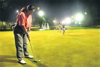 A woman golfer makes the most of a pleasant evening and floodlit golf at the Chandigarh Golf Club.