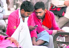 With the railway traffic hit due to agitation in Rajasthan, porters at railway station while away time by playing games on their mobile phone in Ludhiana