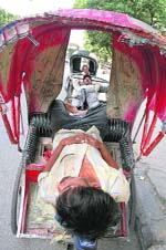 An exhausted rickshaw-pullers takes a nap under the canopy of his rickshaw to beat the heat in Ludhiana on Wednesday.