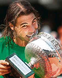 Spains Rafael Nadal bites his trophy after beating Swiss Roger Federer during the final of French Open at Roland Garros in Paris on Sunday.