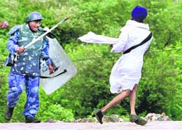 A soldier of the Rapid Action Force runs after a protester on the Eastern Express Highway in suburban Mumbai