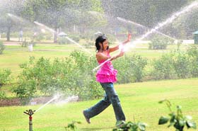 A young girl enjoys being caught between water sprinklers at the Rose Garden in Sector-16, Chandigarh