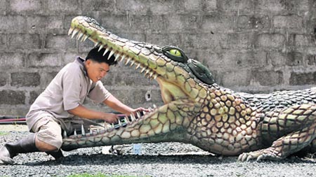 A worker cleans a large model of crocodile in preparation for a live show opening in Manila, Philippines.