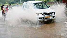 A car splashes rainwater that accumulated on the Sectors 27-28 dividing road in Chandigarh