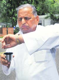 Samajwadi Party president Mulayam Singh Yadav looks at his watch after addressing the media outside the Prime Ministers residence in New Delhi