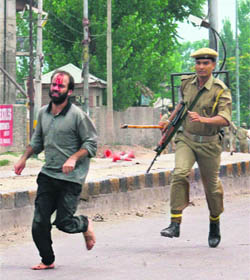 An injured protester, chased by a CRPF soldier, runs for shelter outside a Muslim shrine in the Soura area of Srinagar, where a fire broke out on Saturday.